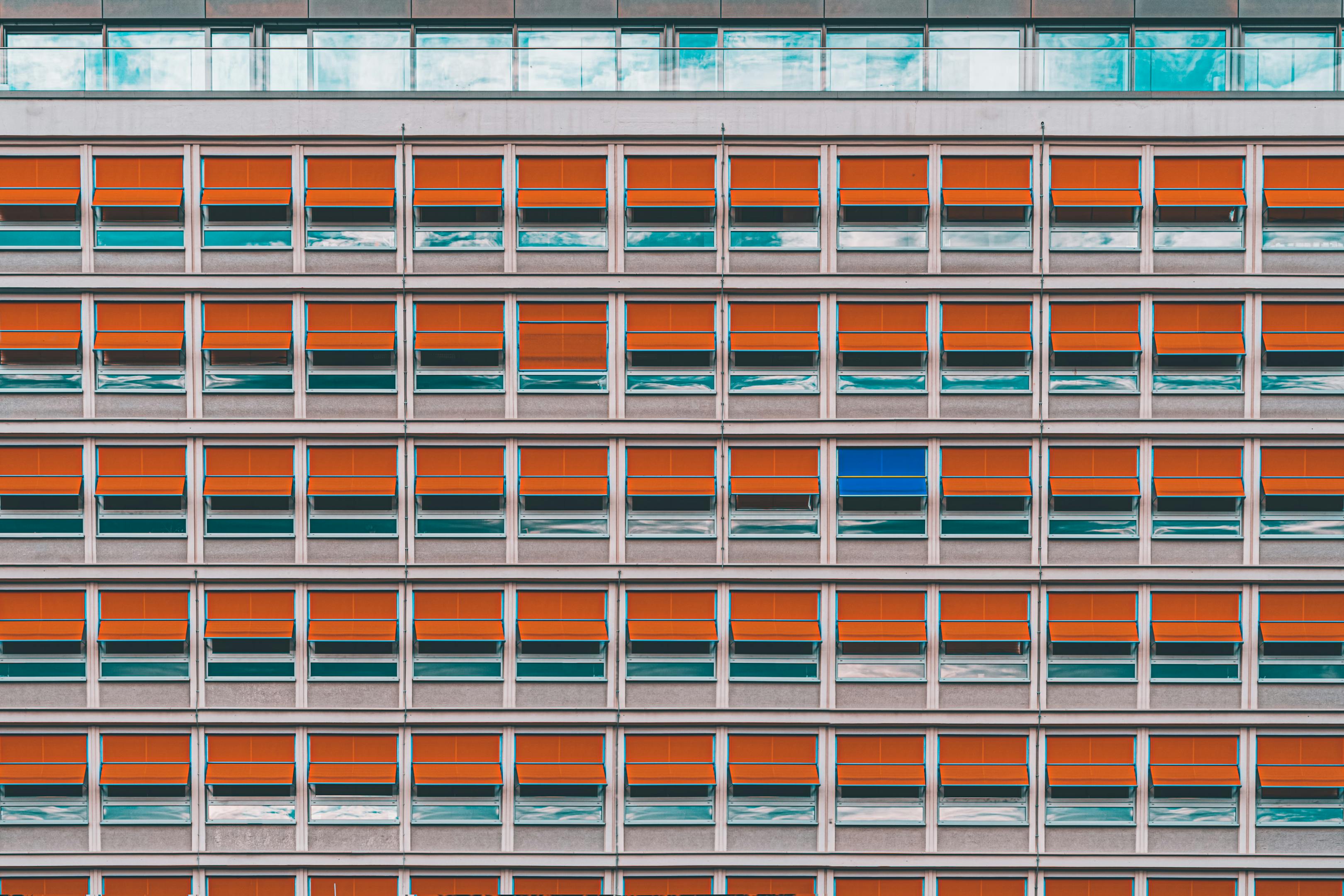Fassade mit außenliegendem orange Sonnenschutz, Beispiel für effektiven baulichen Hitzeschutz nach ASR A3.5