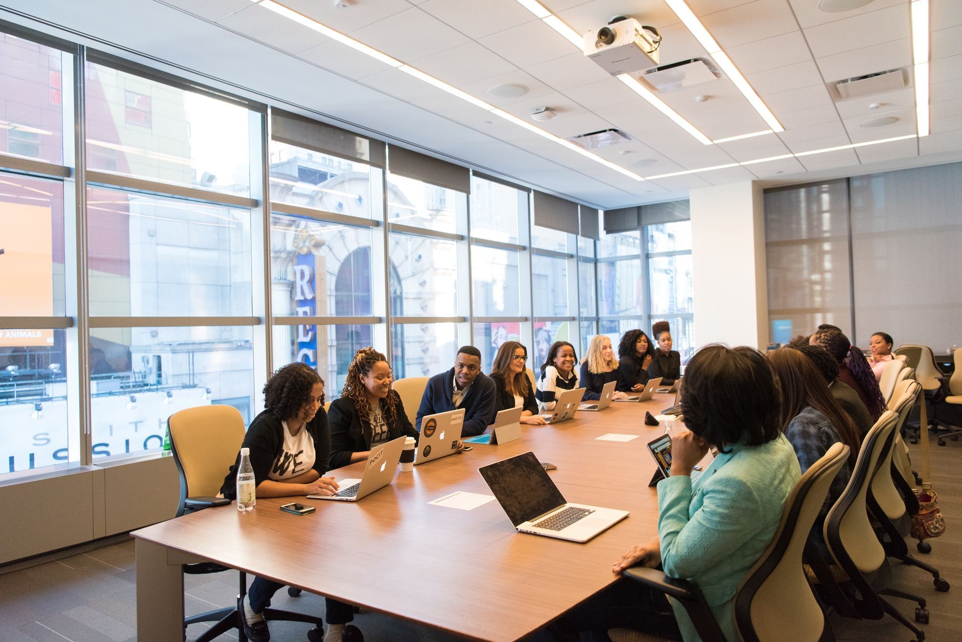 Large team sitting around a conference table in a glass-walled meeting room