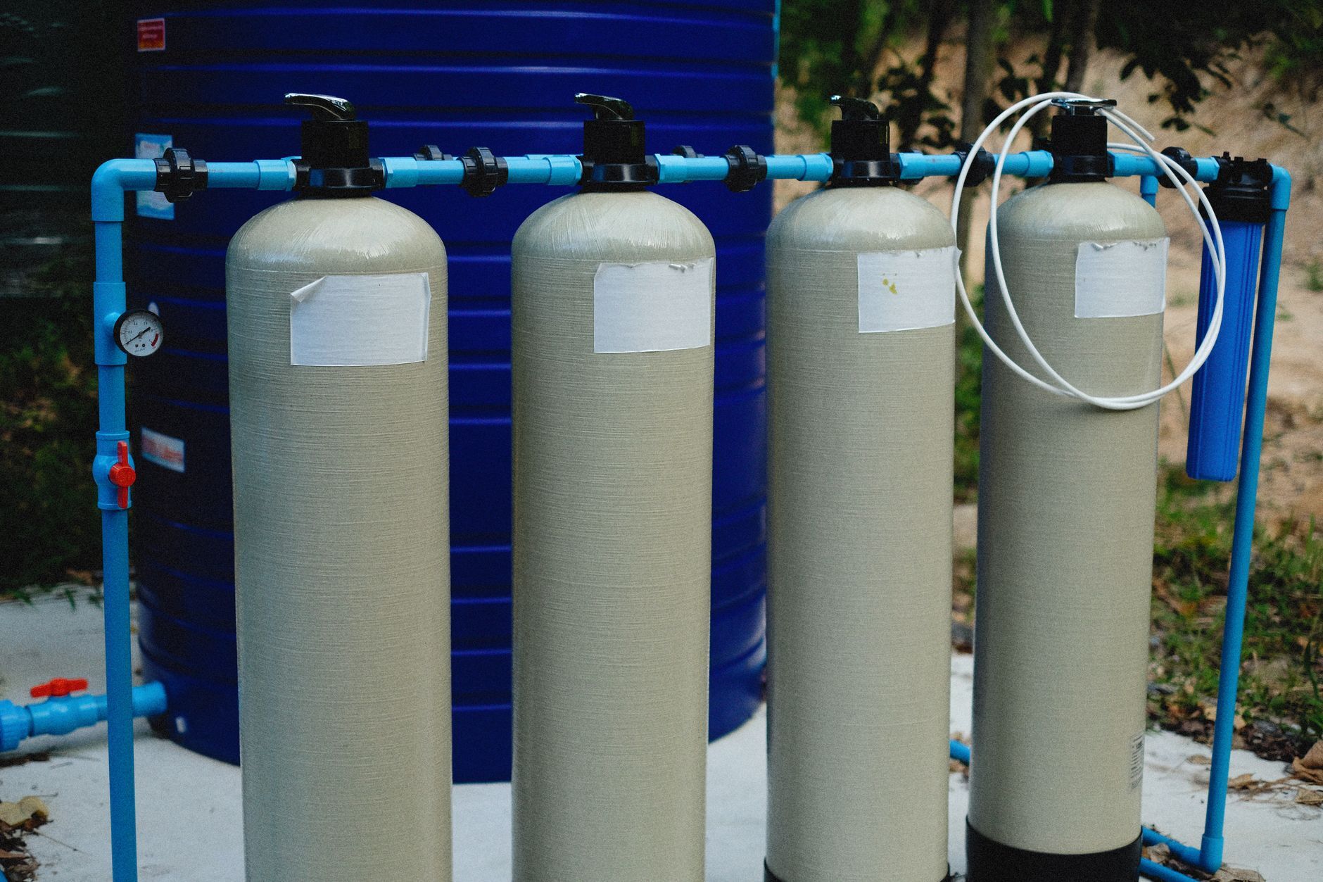 Four filter tanks with blue piping in an outdoor water treatment setup