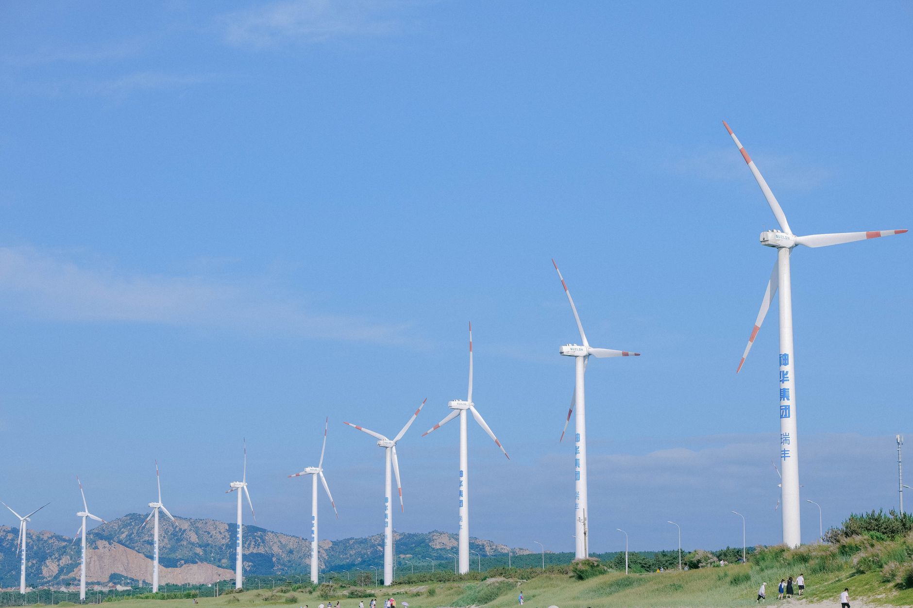 Reihe von Windrädern vor blauem Himmel an der Küste von Weihai
