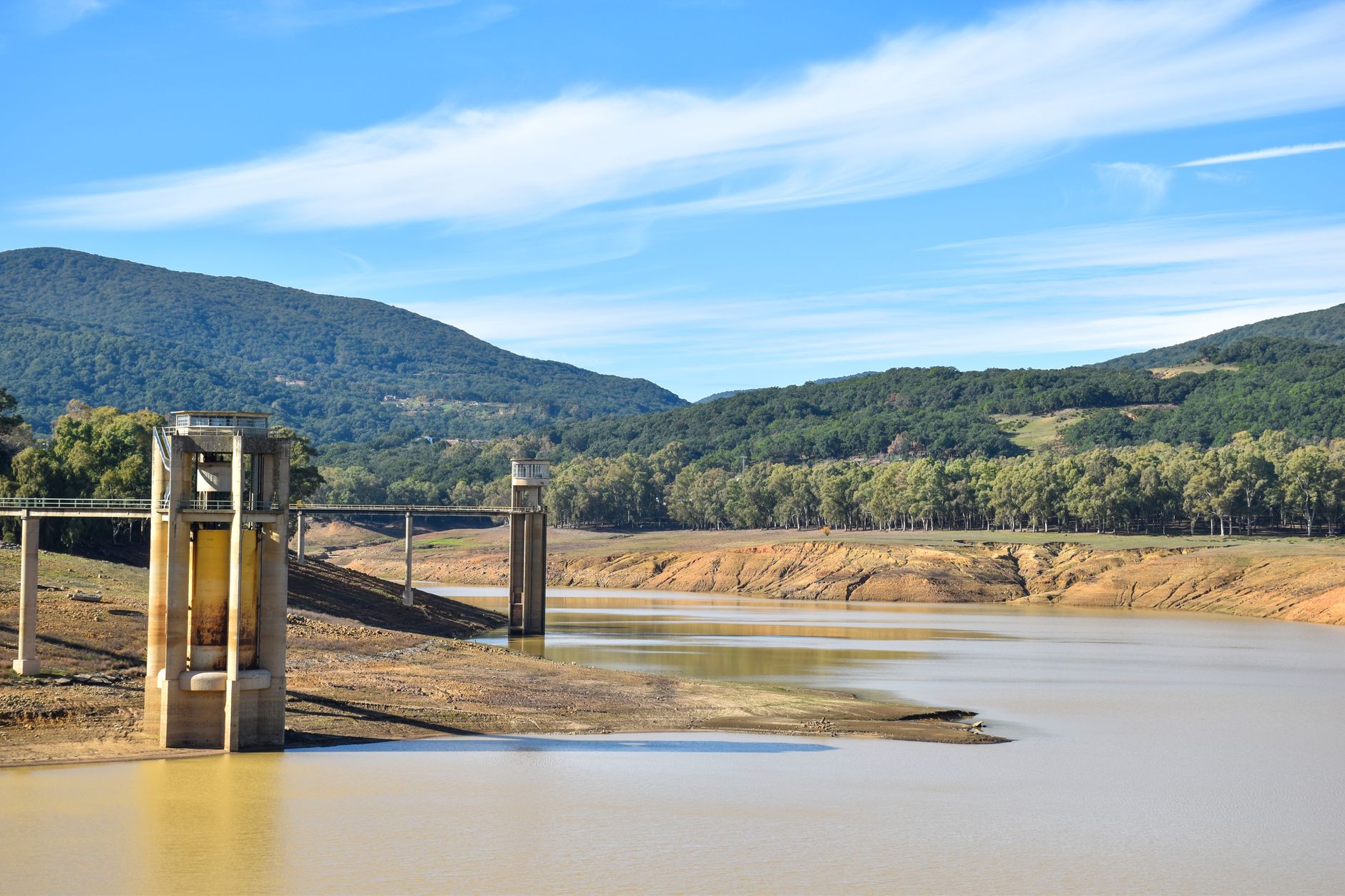 Reservoir with a low water level surrounded by forested hills