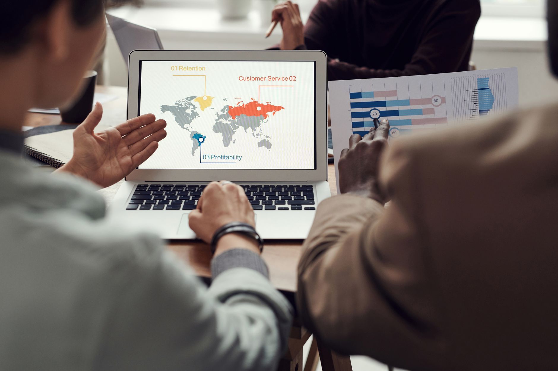 Team in a discussion around a laptop showing a world map