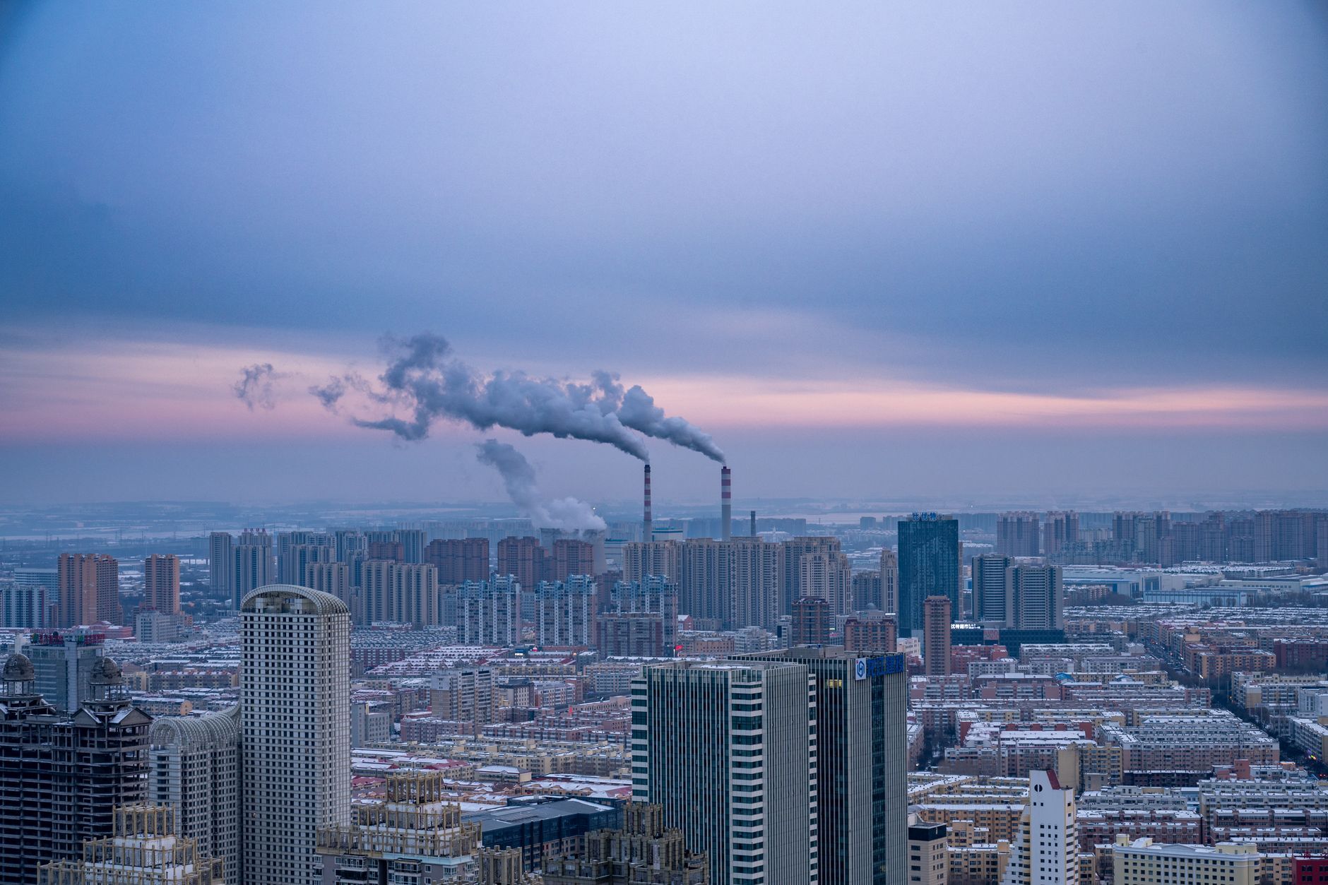 Rauchende Schornsteine über der Skyline von Harbin in der Morgendämmerung