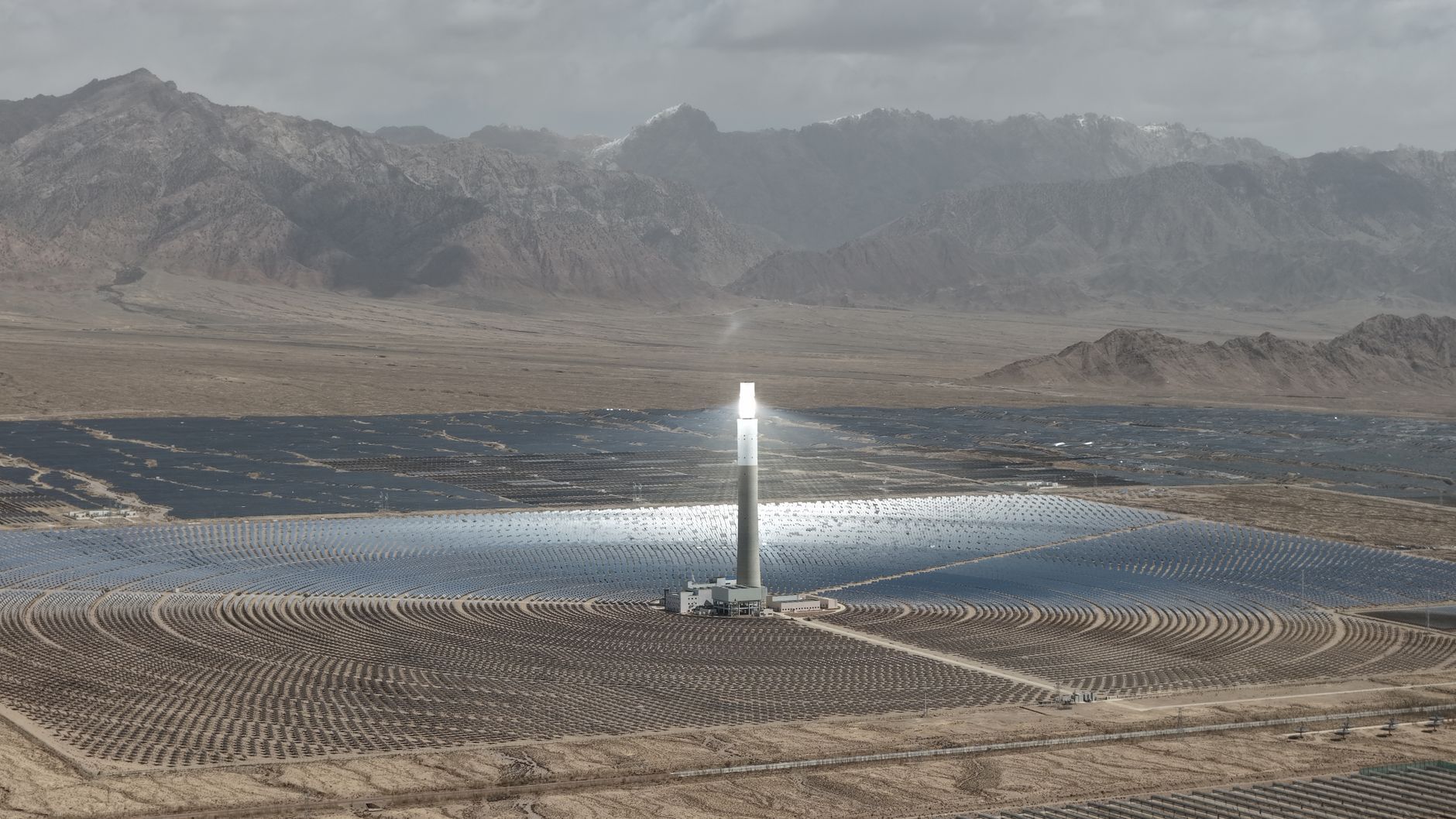 Solar thermal power plant with a central tower in a desert in front of mountains