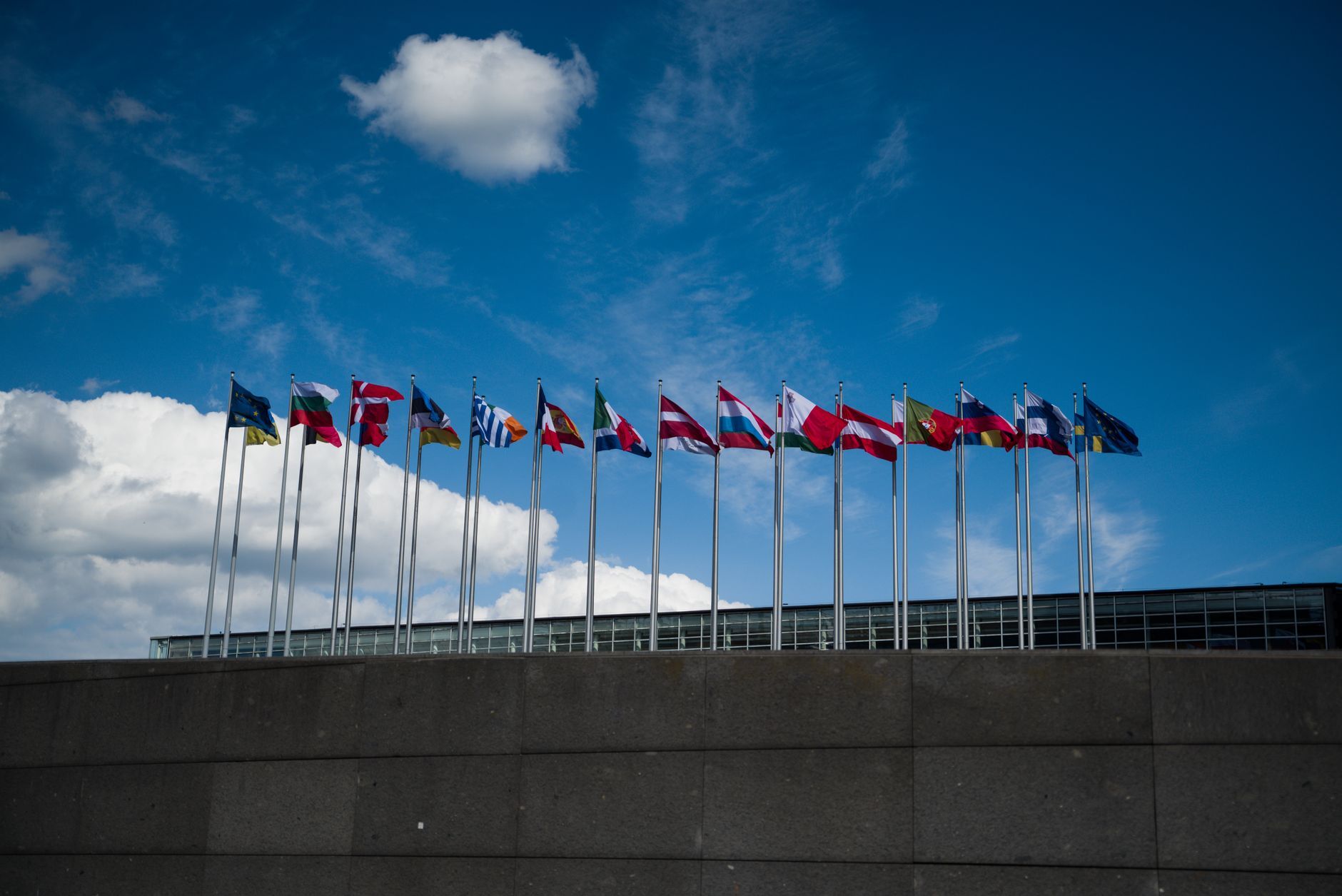 Row of European national flags in front of a building under a blue sky