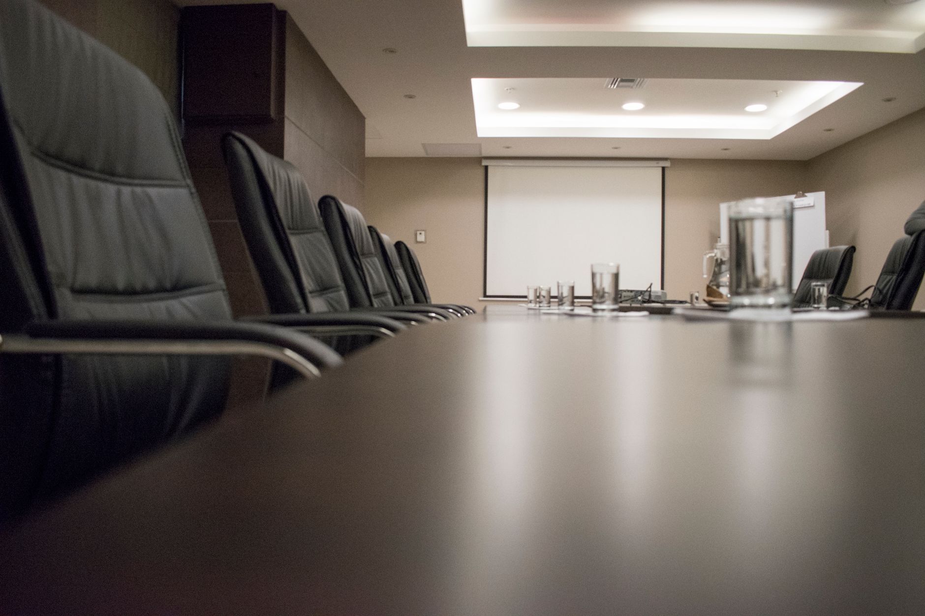 Empty conference room with a long table and black chairs