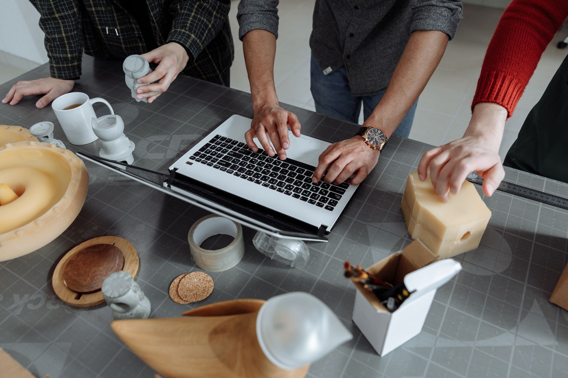 Team working on product prototypes around a laptop in a workshop