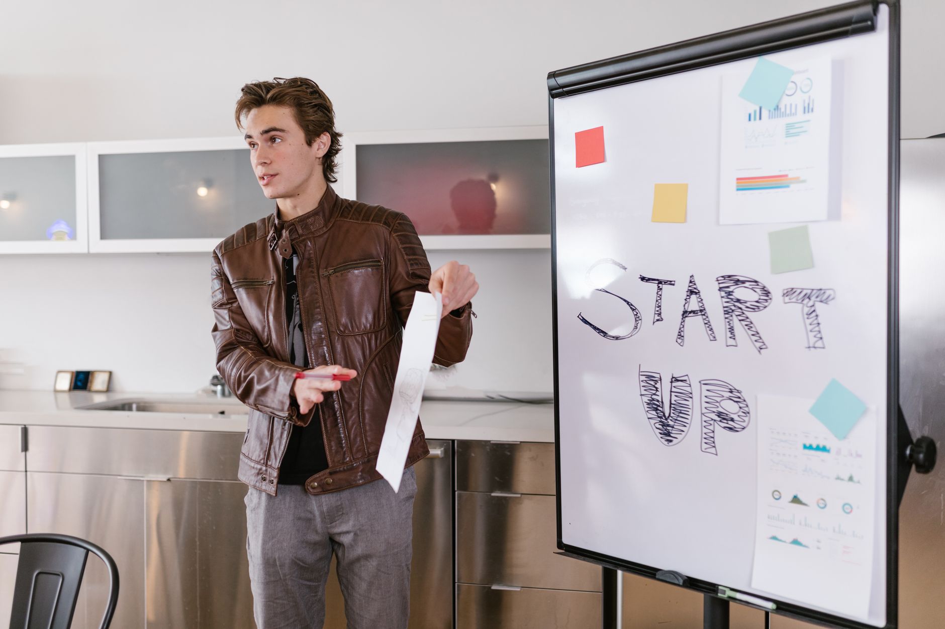 Young founder presenting at a flipchart with the word Startup
