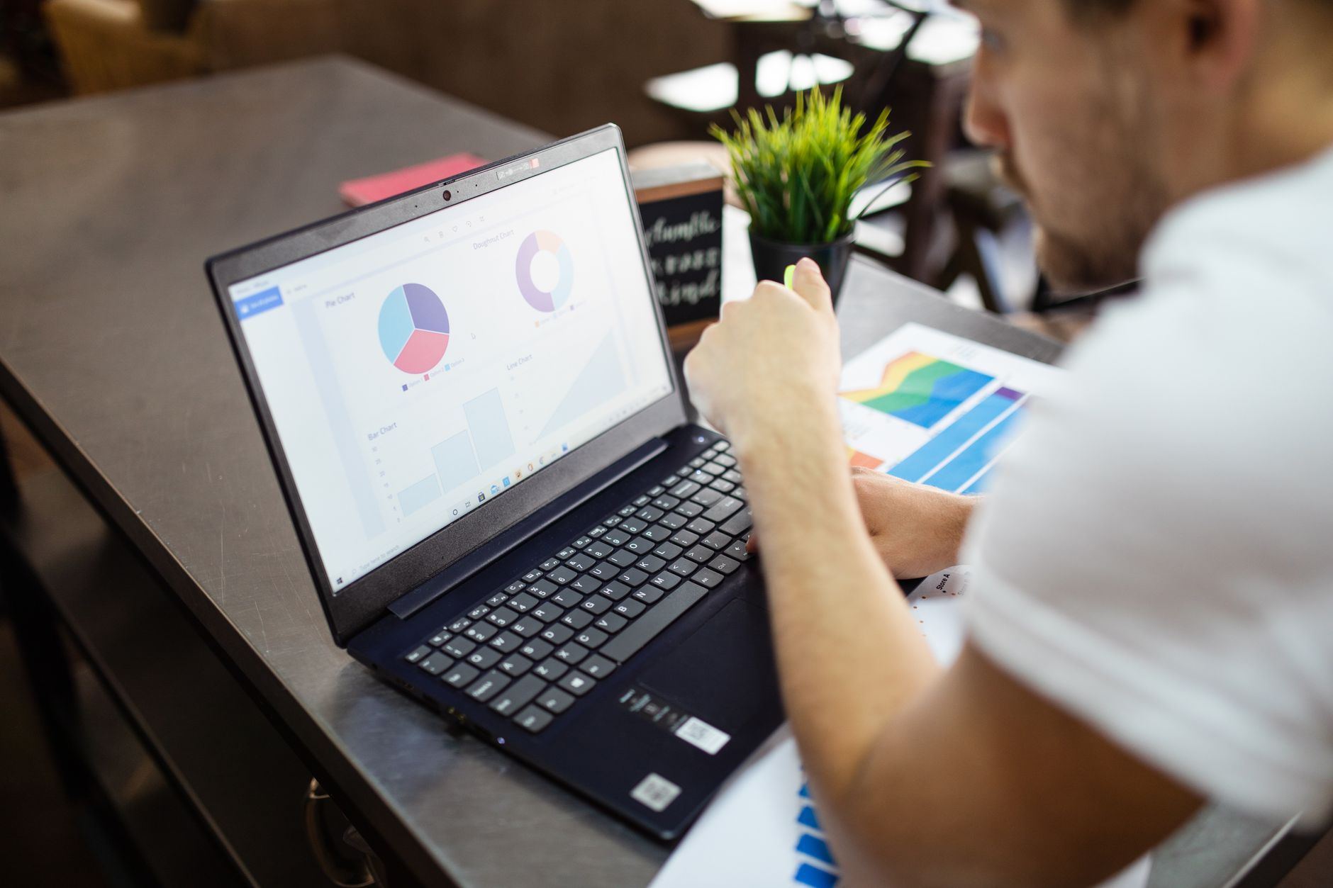 Mann arbeitet an einem Laptop mit Diagrammen auf dem Bildschirm